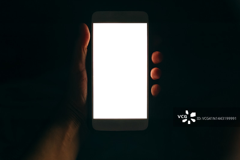 黑暗中人手中的白色屏幕手机图片素材