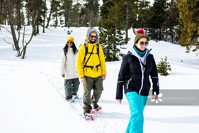 三个年轻人在雪地里穿着雪鞋徒步旅行图片素材