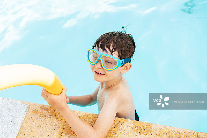 戴着护目镜的白人小男孩在游泳池边图片素材