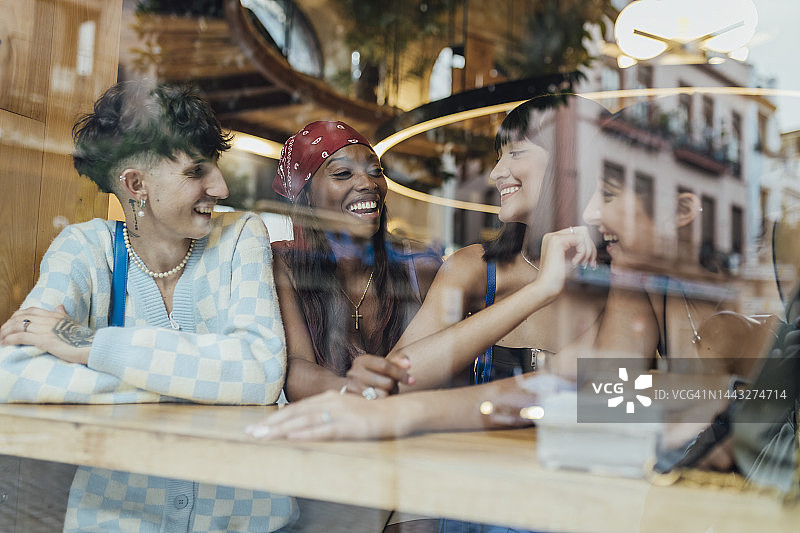 透过玻璃看到的在咖啡馆里聊天的快乐朋友们图片素材