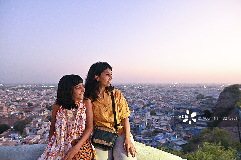 母女游客坐在山顶欣赏城市黄昏景色图片素材