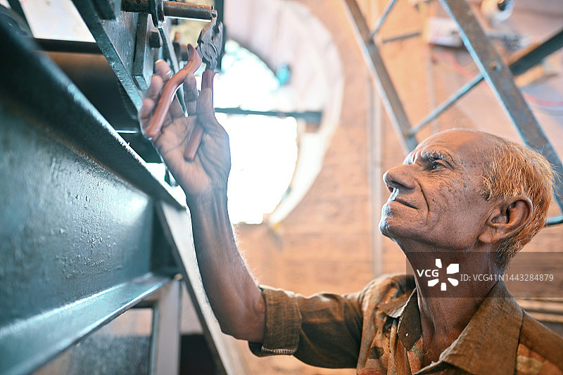 维护钟楼老式时钟机械的年长男人图片素材