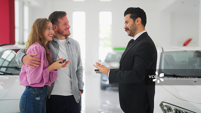 情侣在展厅从汽车销售员手中接过新车钥匙图片素材