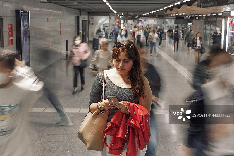 在拥挤的地铁站查看智能手机的拉丁妇女图片素材