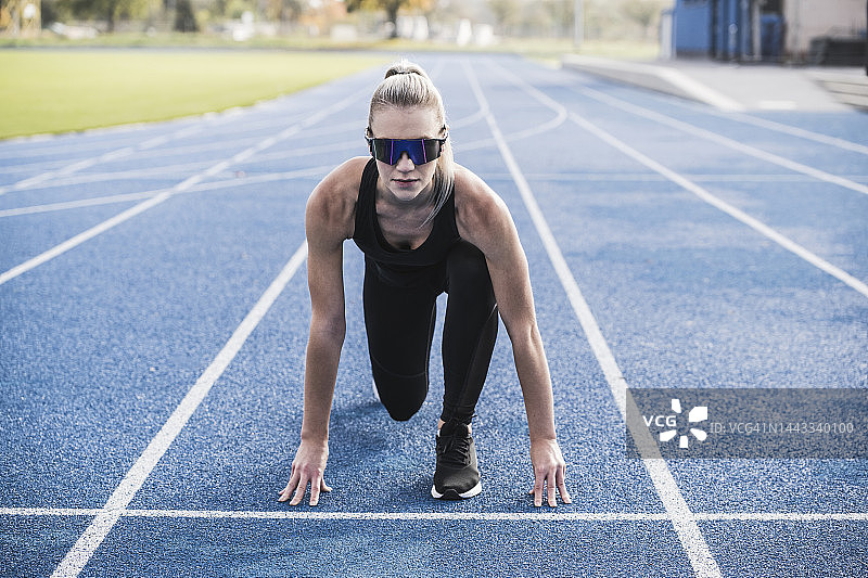 年轻女运动员在跑道起跑线上戴着智能眼镜图片素材