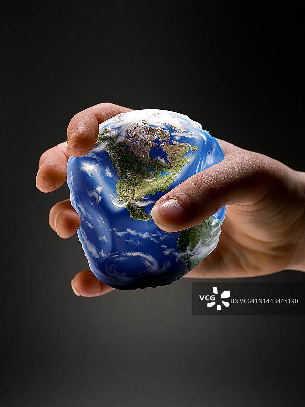 手握住部分放气的塑料地球仪图片素材