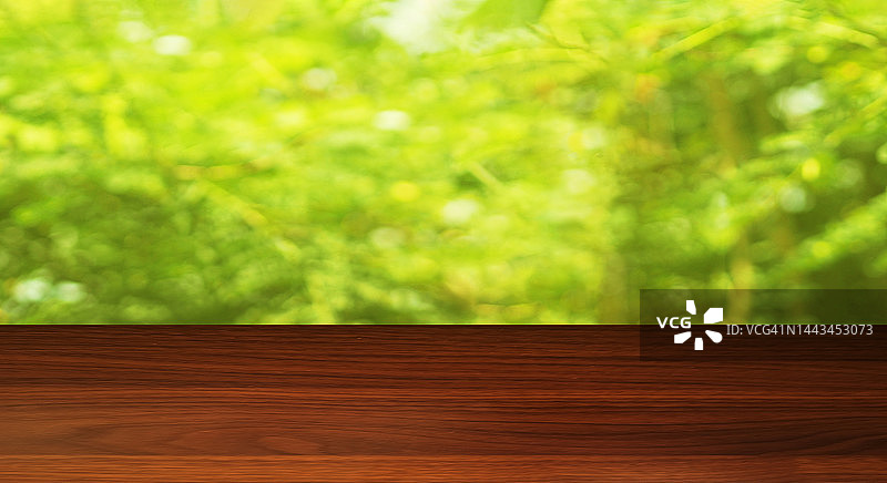 用于产品展示的棕色木桌，背景为模糊的绿色自然图片素材