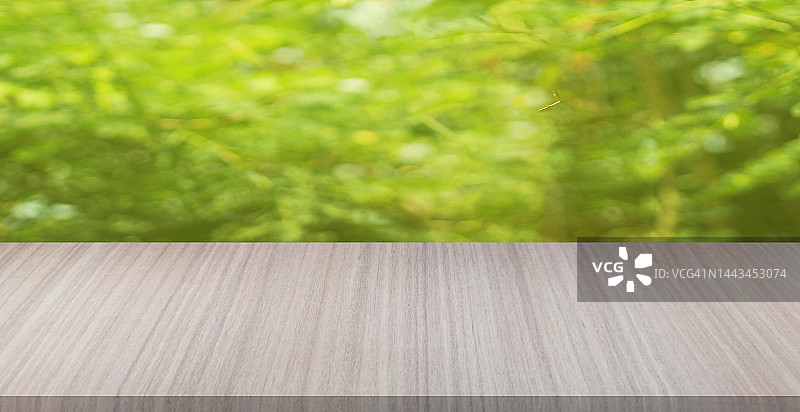 用于产品展示的棕色木桌，背景为模糊的绿色自然图片素材