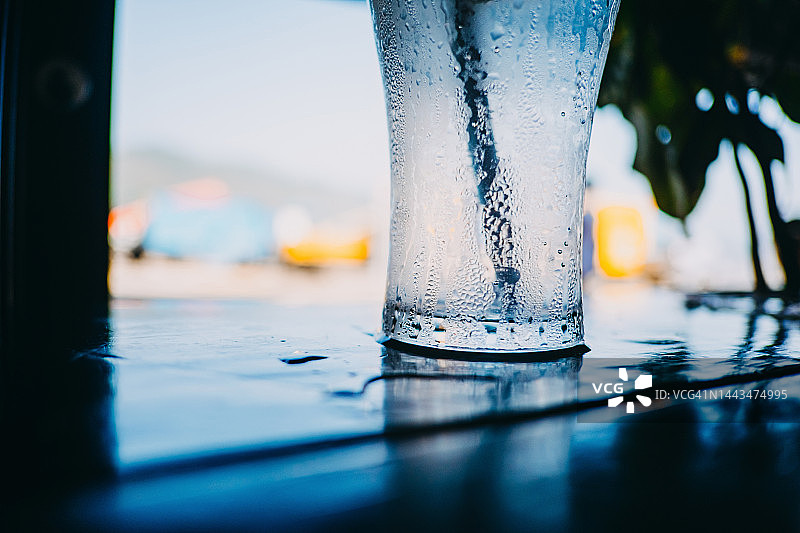 阳光明媚的蓝天下，户外餐厅桌上的一杯冰镇苏打水图片素材