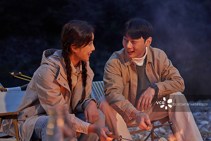 情侣在篝火旁烤玉米和香肠图片素材