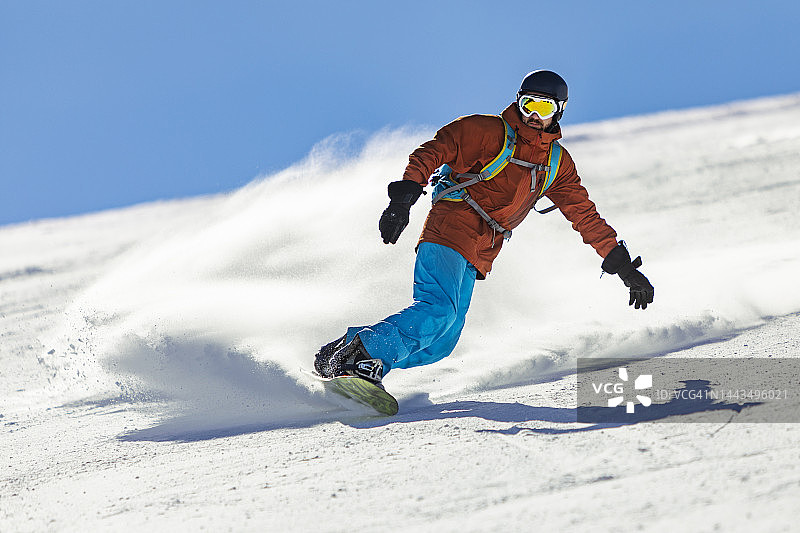 青年男子在滑雪胜地的山区滑雪图片素材