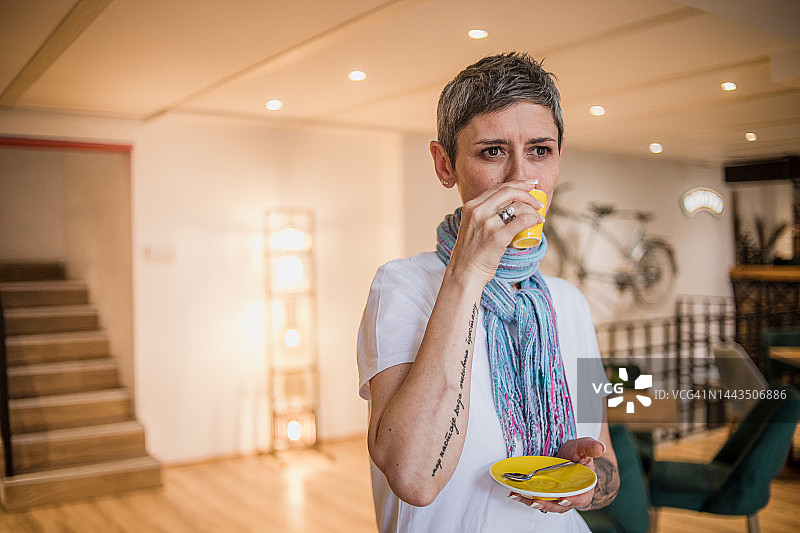 一位中年妇女站在自助餐厅喝咖啡图片素材