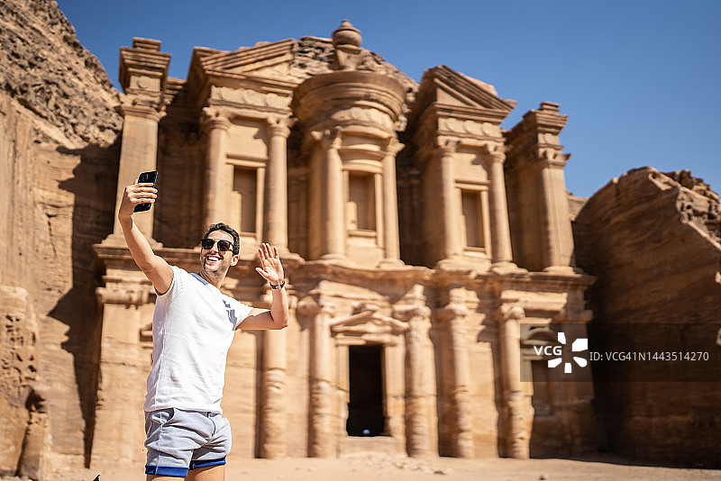 中年男人在约旦佩特拉旅游，用手机自拍或拍摄图片素材