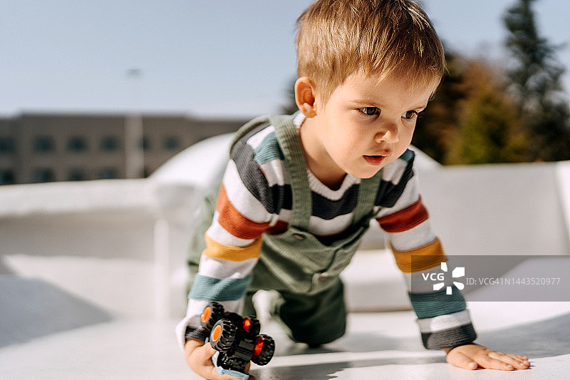 可爱幼儿在户外玩玩具车图片素材