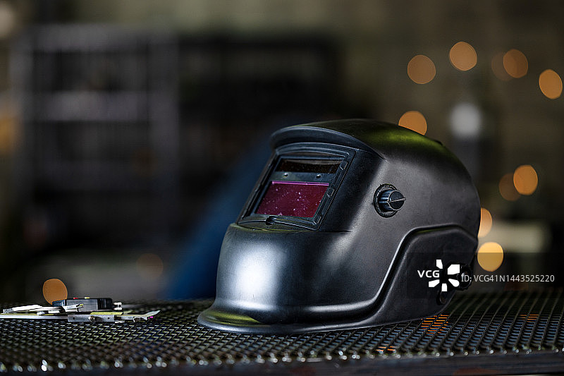 金属重工业焊接和切割期间的辐射能量眼部防护，用于焊工技术人员眼部保护的钢栅栏上的自动变光焊接头盔图片素材