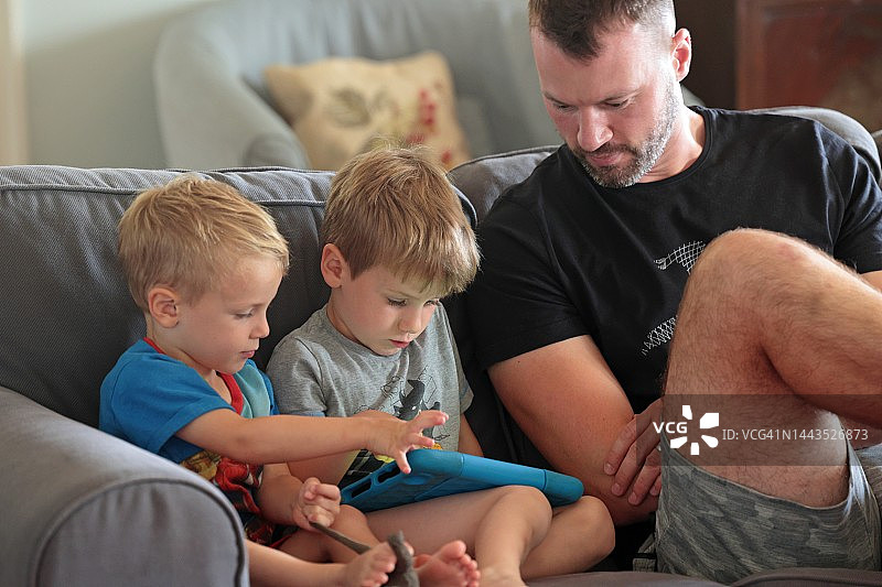 父亲看孩子们玩平板电脑图片素材