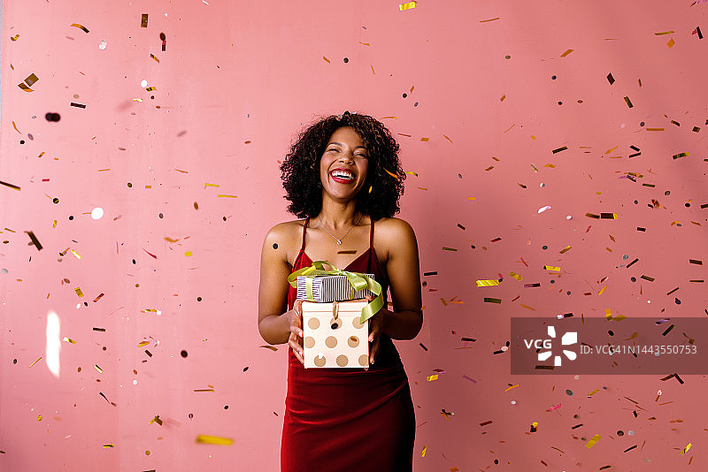 站在五彩纸屑雨中手捧鲜花的快乐女人图片素材