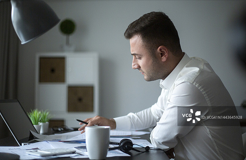 专注的商人在办公桌前使用笔记本电脑工作图片素材