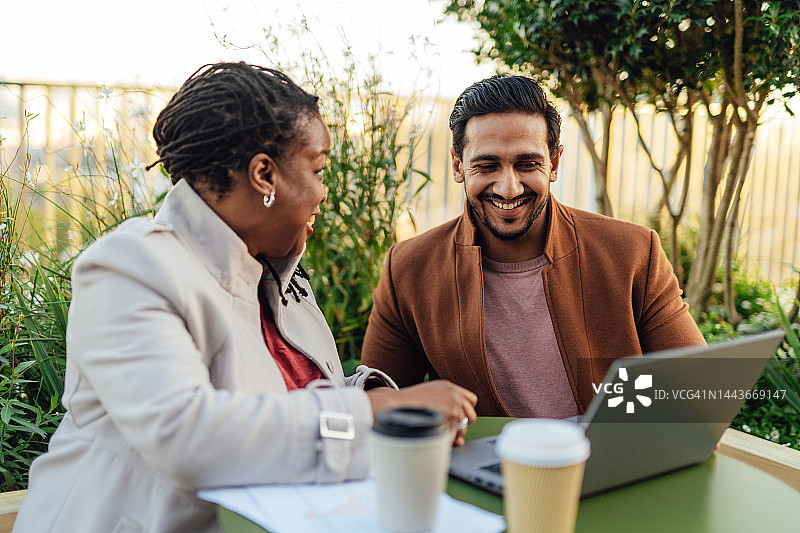 同事在高层办公楼屋顶花园开会讨论项目图片素材