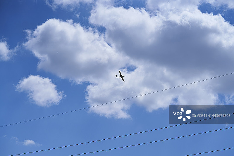 仰视蓝天白云下飞机飞过瞬间，可见电线图片素材