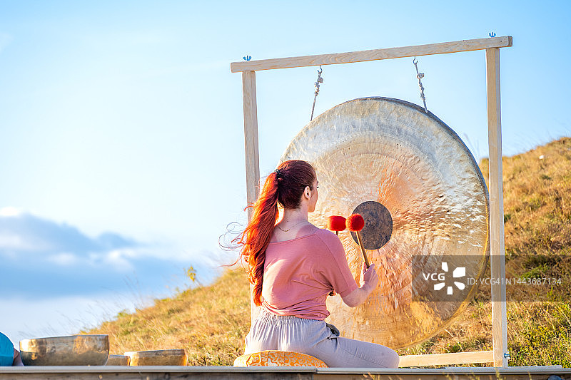 音疗：女子击打铜锣（背面视角）图片素材