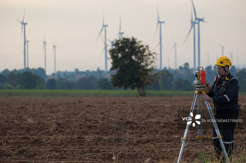 老年男工程师在风力发电机场使用经纬仪图片素材