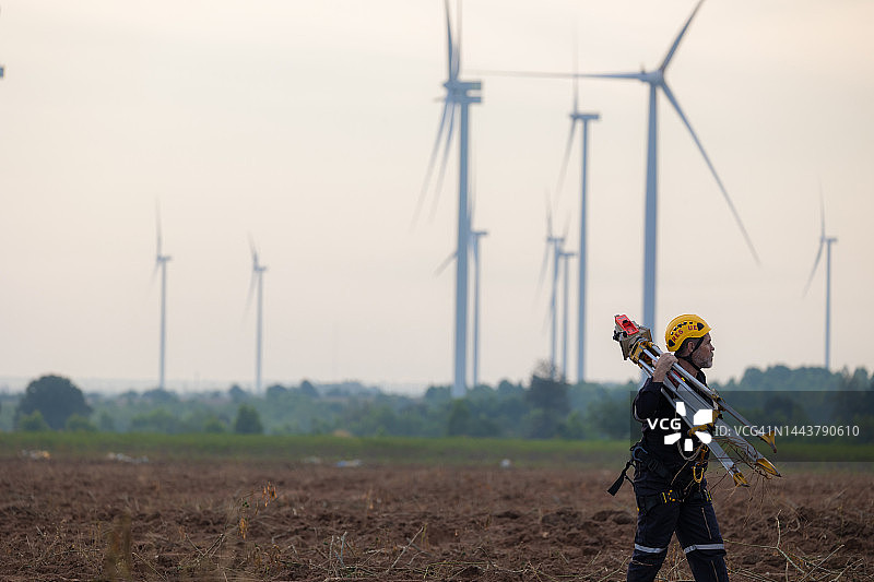 老年男工程师在风力发电机场使用经纬仪图片素材