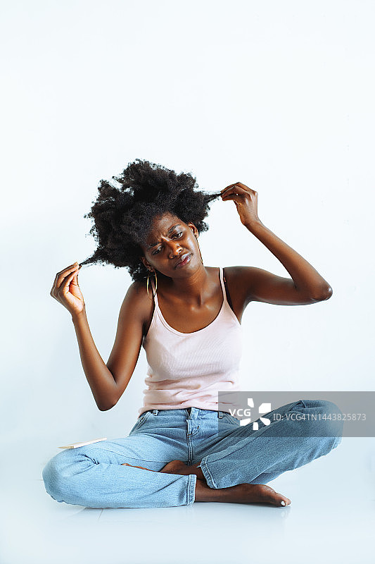 干燥多孔的卷曲非洲发型问题，女子沮丧地拿着一缕头发图片素材