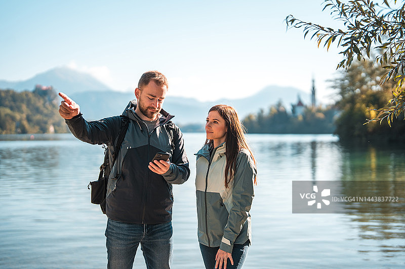 在高山湖泊旁观看山峰的白人男女朋友图片素材