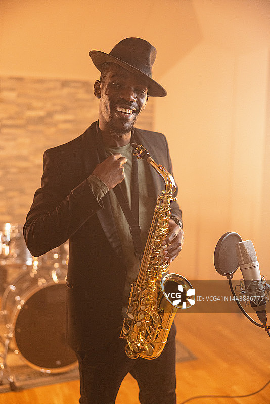 成年黑人男音乐家拿着萨克斯风对着镜头微笑图片素材
