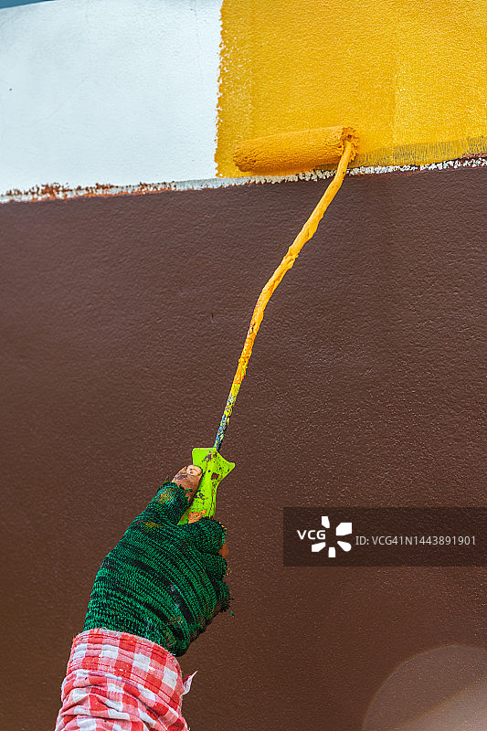 画家用橙色滚筒粉刷美丽住宅的水泥围栏图片素材