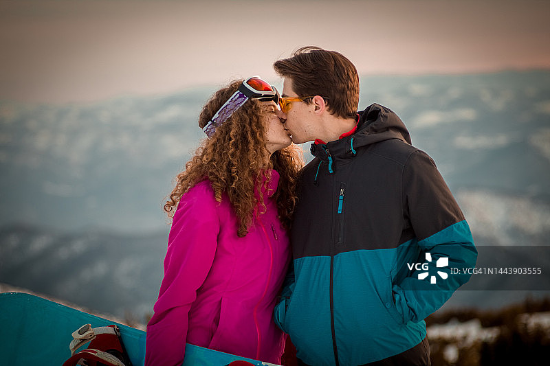 寒冷冬日山顶上亲吻的年轻情侣图片素材