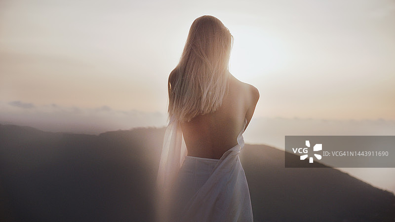 金色夕阳下身着白色长袍的金发女神图片素材