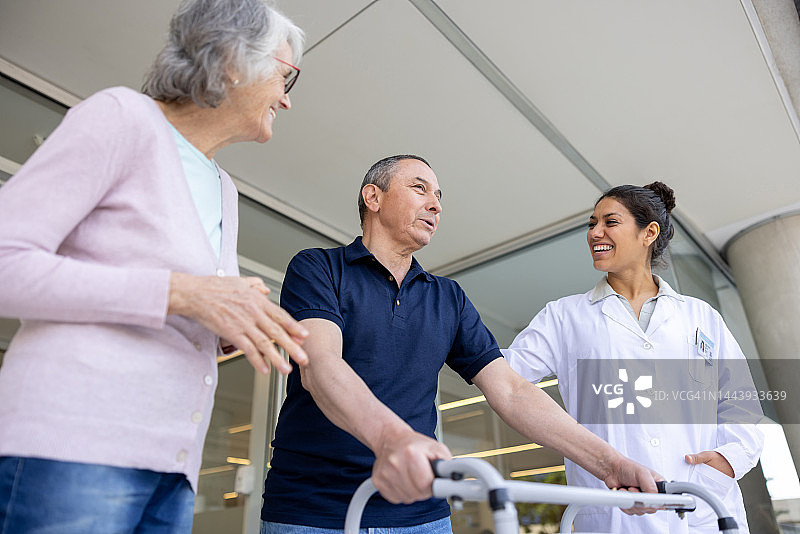 快乐的医生在门口与离开医院的病人交谈图片素材