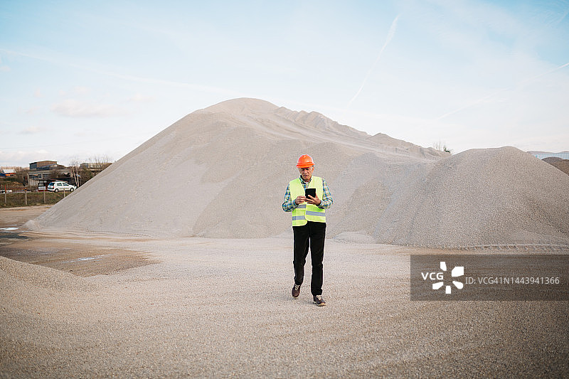 年长的成年男人在建筑工地使用数位平板电脑图片素材