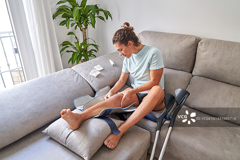 膝盖手术后在家治疗腿部的女人图片素材