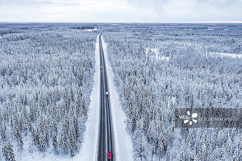 冰雪路面上行驶的汽车进入雪林的鸟瞰图图片素材