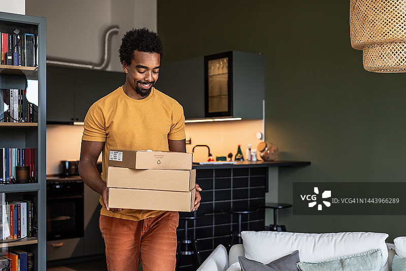 在客厅里拿着快递盒的年轻男人图片素材