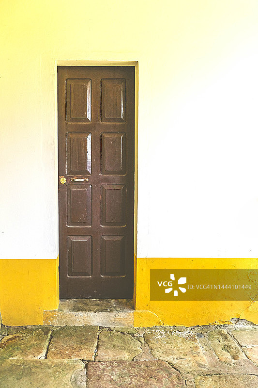 紧闭的白色和黄色墙壁上的老木门图片素材