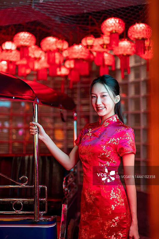身穿红色中式旗袍、在嘟嘟车旁摆酷的年轻亚裔女模特影棚肖像照图片素材