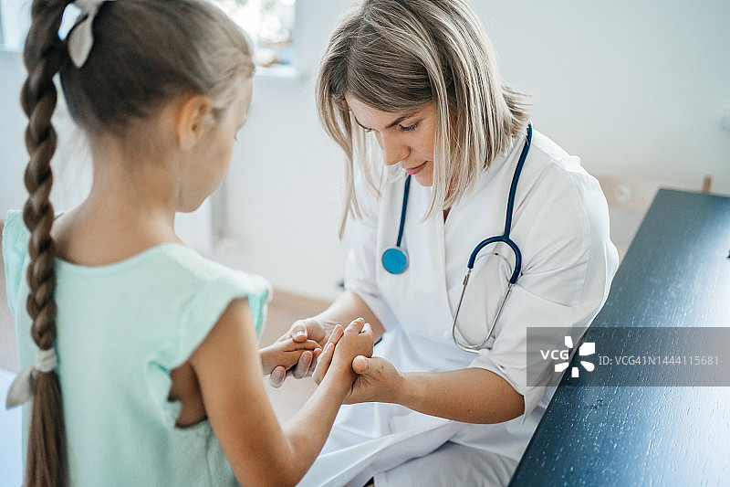 女儿科医生检查生病的孩子的手图片素材