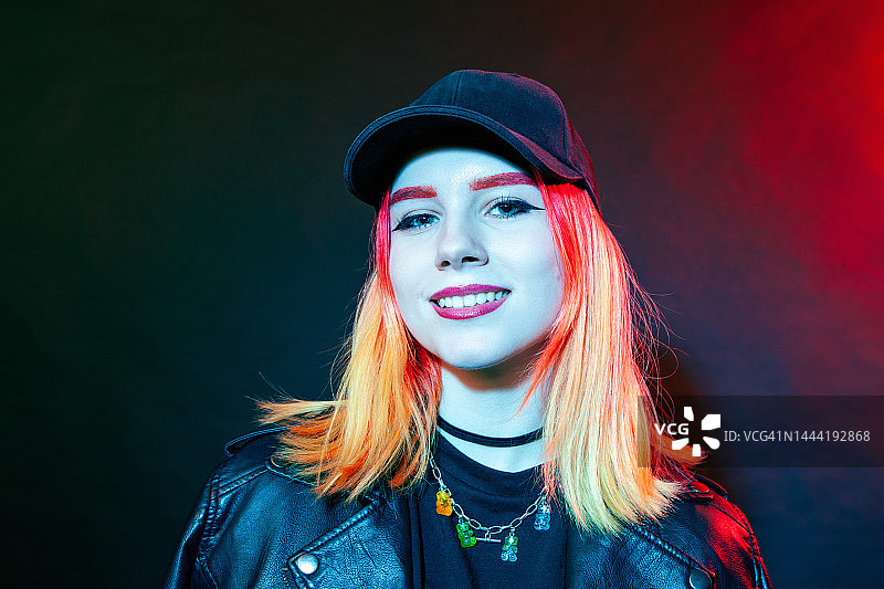黑色背景下，身穿黑色皮夹克的18岁染发白人女性的特写图片素材