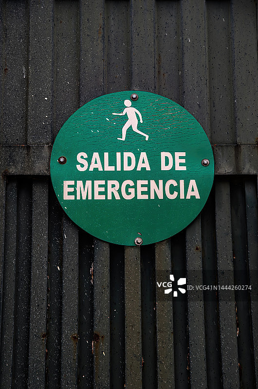 工厂金属门上的西班牙语“紧急出口”标志图片素材