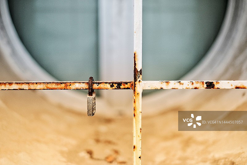 锈迹斑斑的挂锁卡在窗户栏杆上图片素材