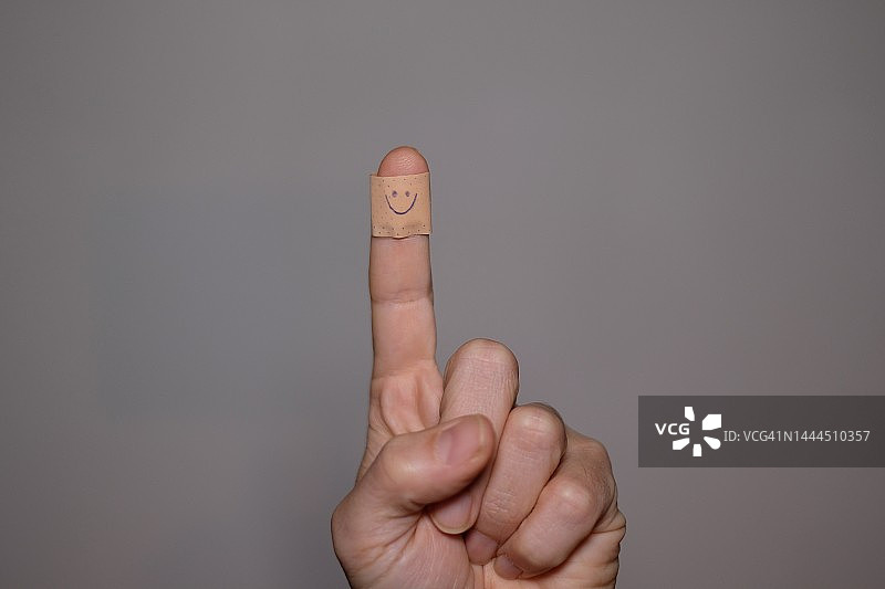 食指上的医用贴片，画着一个微笑图片素材