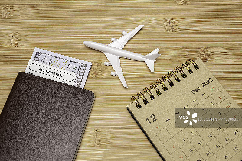 2022年桌面日历：12月是规划和截止日期月，配飞机模型、美元钞票和泰国登机牌，旅行概念图片素材