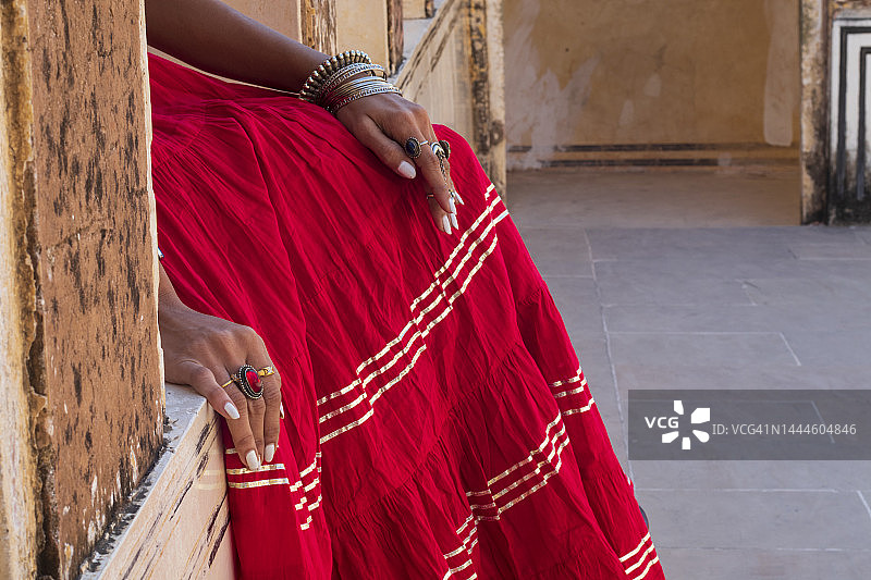 红色裙子的女人，戴着戒指和手镯的手部特写图片素材