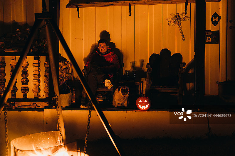 男子在篝火旁享受万圣节之夜的剪影图片素材