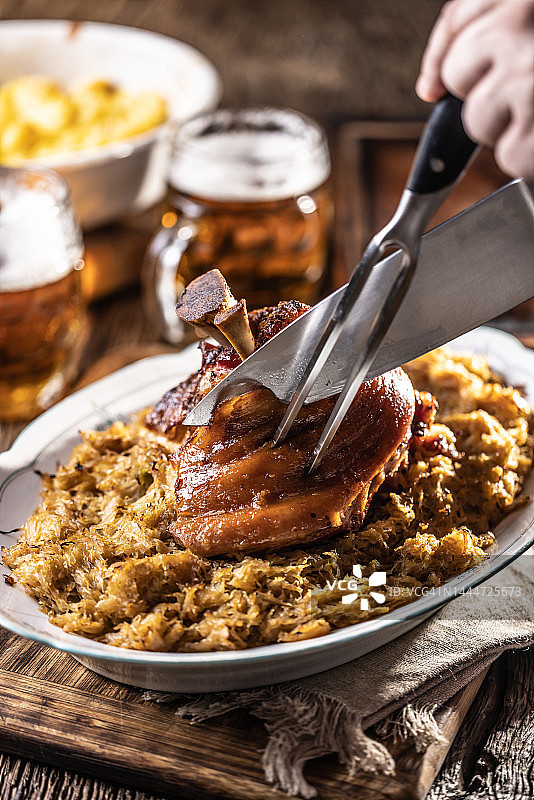 厨师用手切开新鲜出炉的巴伐利亚猪肘和酸菜图片素材