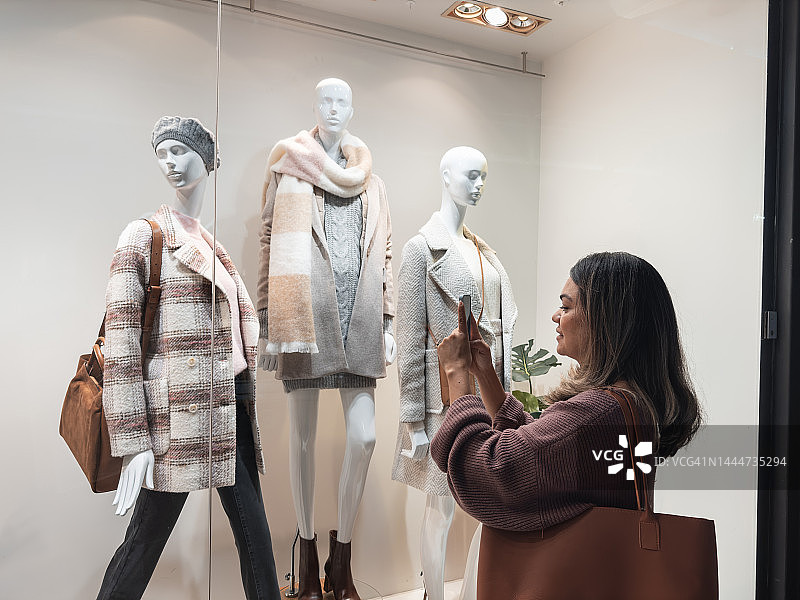 女人看着服装店橱窗里的模特图片素材